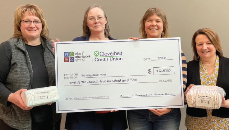 Staff members hold a large promotional check. 