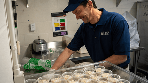 An Elan volunteer packs salad into containers at a food pantry. 