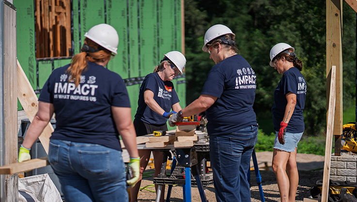 Elan volunteers cutting wood with a saw