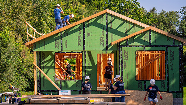 A group of volunteers works on a house under construction. 