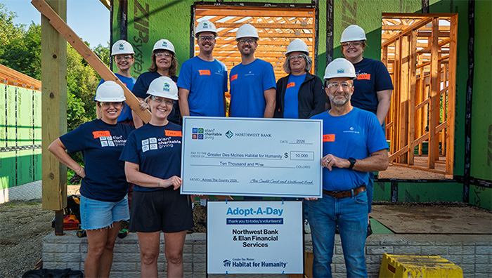 Representatives of Elan Credit Card and Northwest Bank holding a large promotional check in front of the Habitat for Humanity house.
