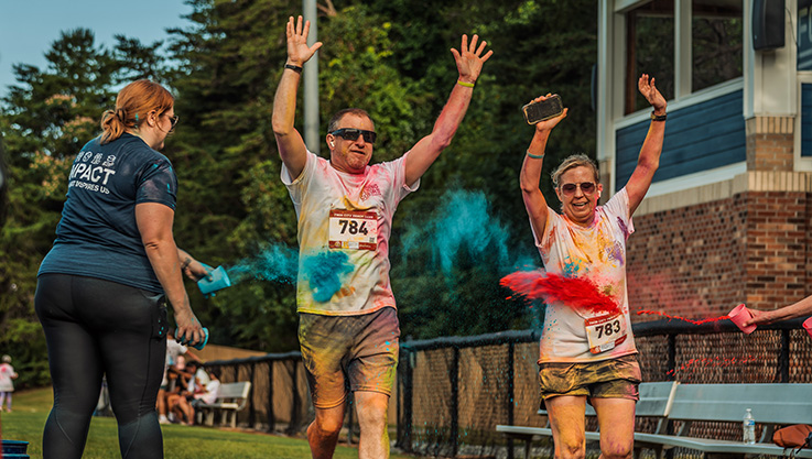An Elan Credit Card volunteer tosses color on two fun run 5k participants at an Elan Charitable Giving event in North Carolina.