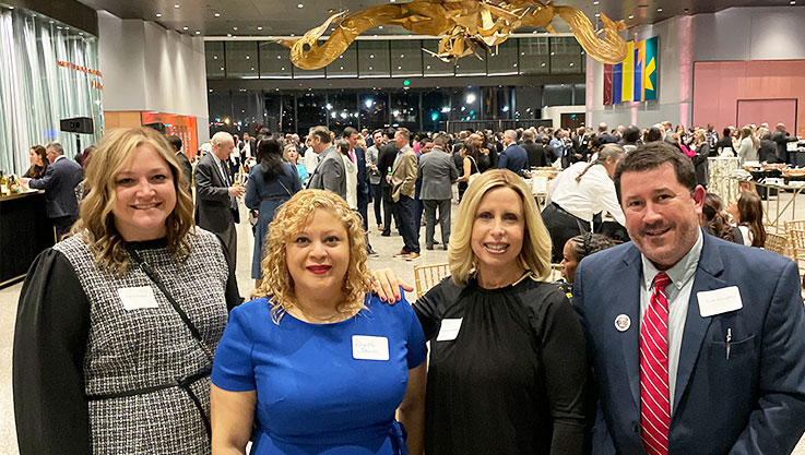 Four Elan Credit Card employees stand together in the lobby of a museum. 