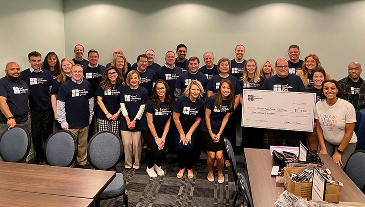 Group photo of the Elan Team with a big check