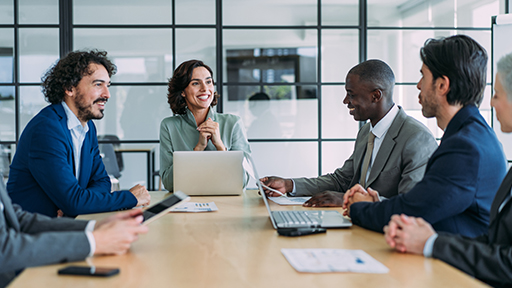 Four business people sit around a conference table in discussion. 
